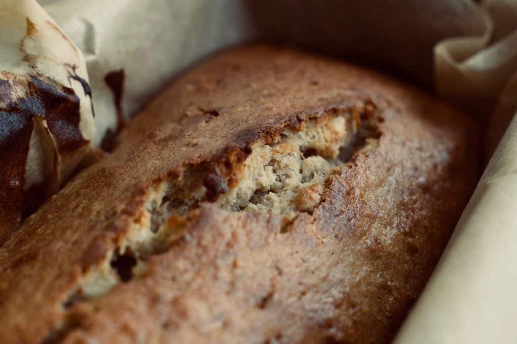 Banana bread in loaf pan with parchment paper.