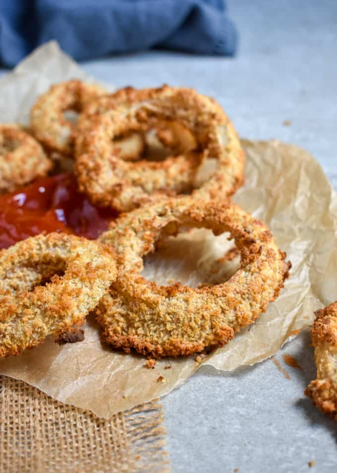 Crunchy baked onion rings around ketchup.