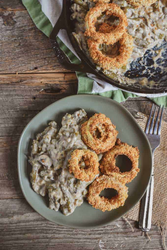 Vegan green bean onion ring casserole on plate with fork and skillet.