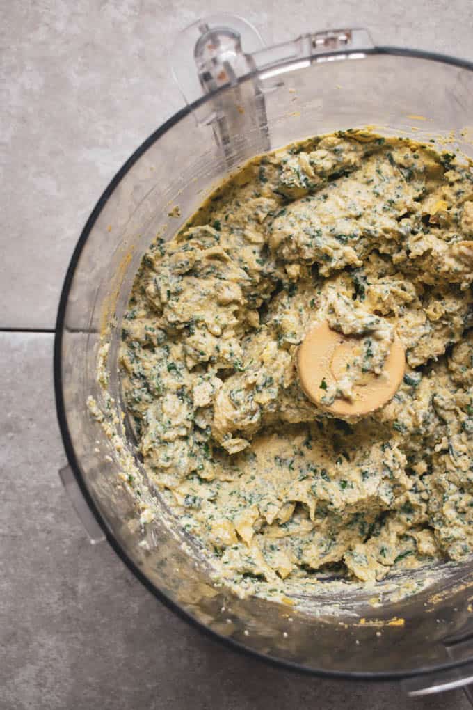 Creamy vegan spinach artichoke dip ingredients blended in a food processor.