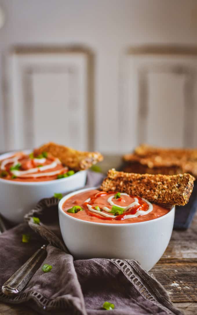 Creamy vegan tomato soup with cashew cream and toasted bread on table.
