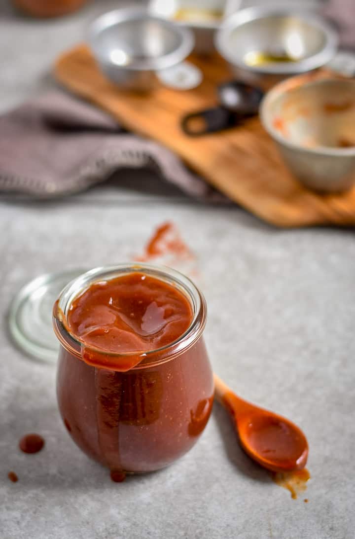 Easy homemade bbq sauce on table with spoon and ingredients.