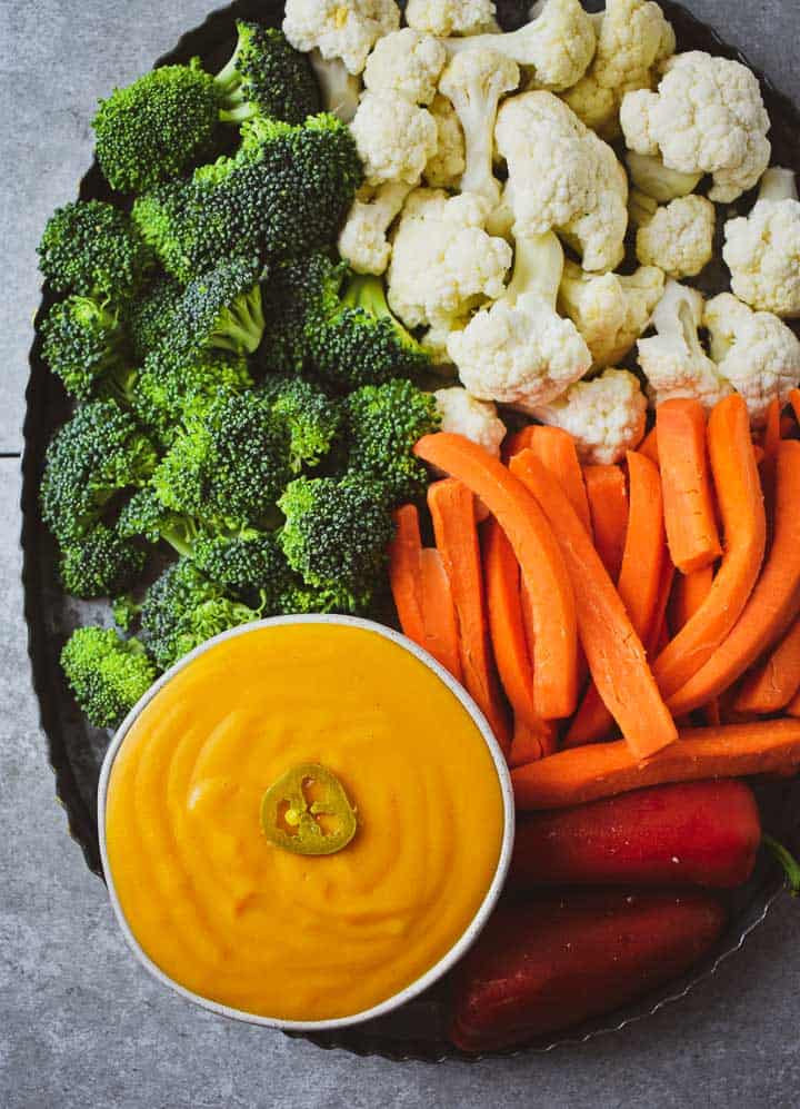 Vegan cheese sauce on veggie platter with broccoli, cauliflower, carrots, and peppers.