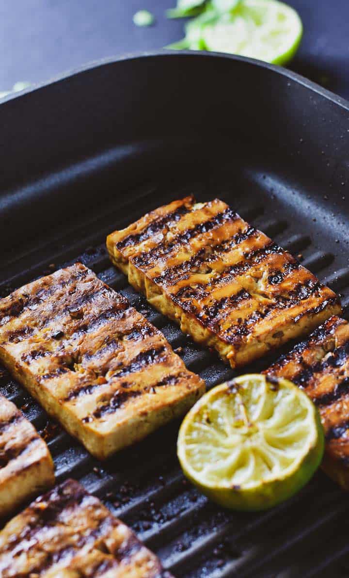 Marinated tofu in grill pan with a lime.