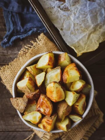 Oil-free oven roasted potatoes in a bowl on burlap napkin with baking sheet