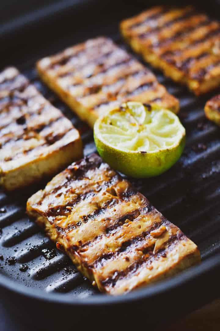Grilled marinated tofu in grill pan with a lime.