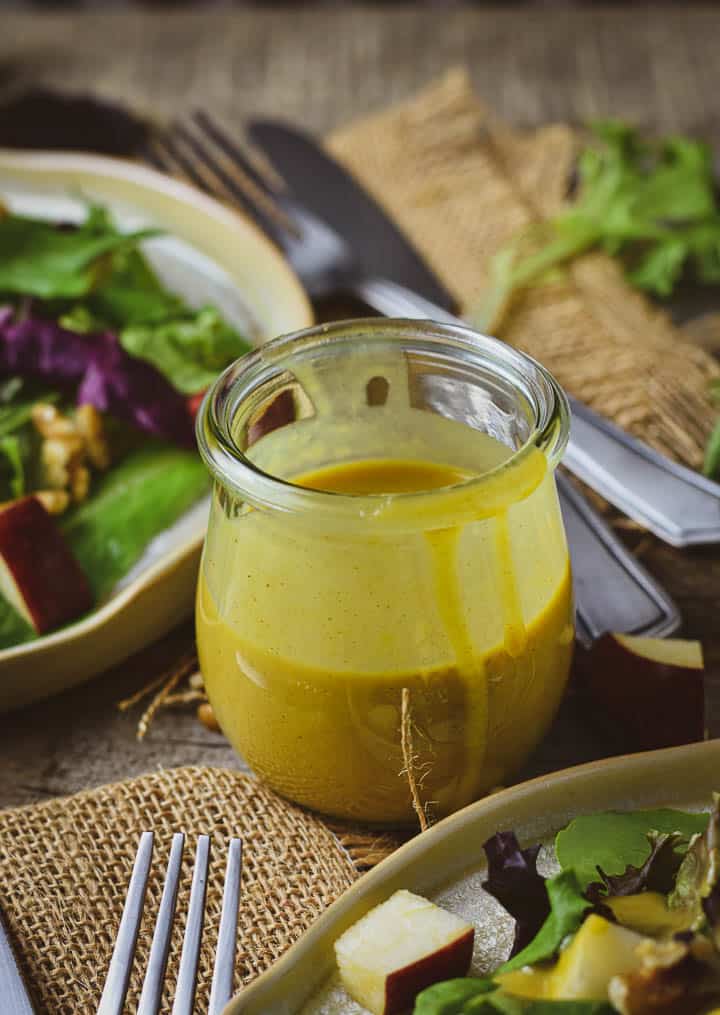 Vegan Honey Mustard dressing in a jar on table with salad.