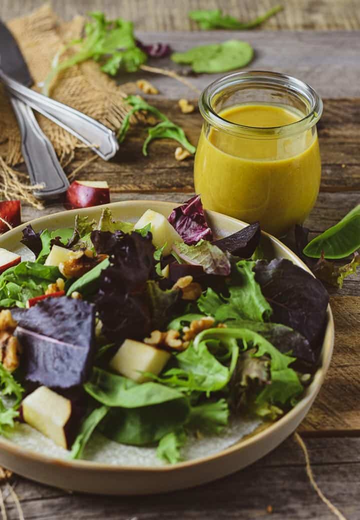 Salad on plate with jar of honey mustard.