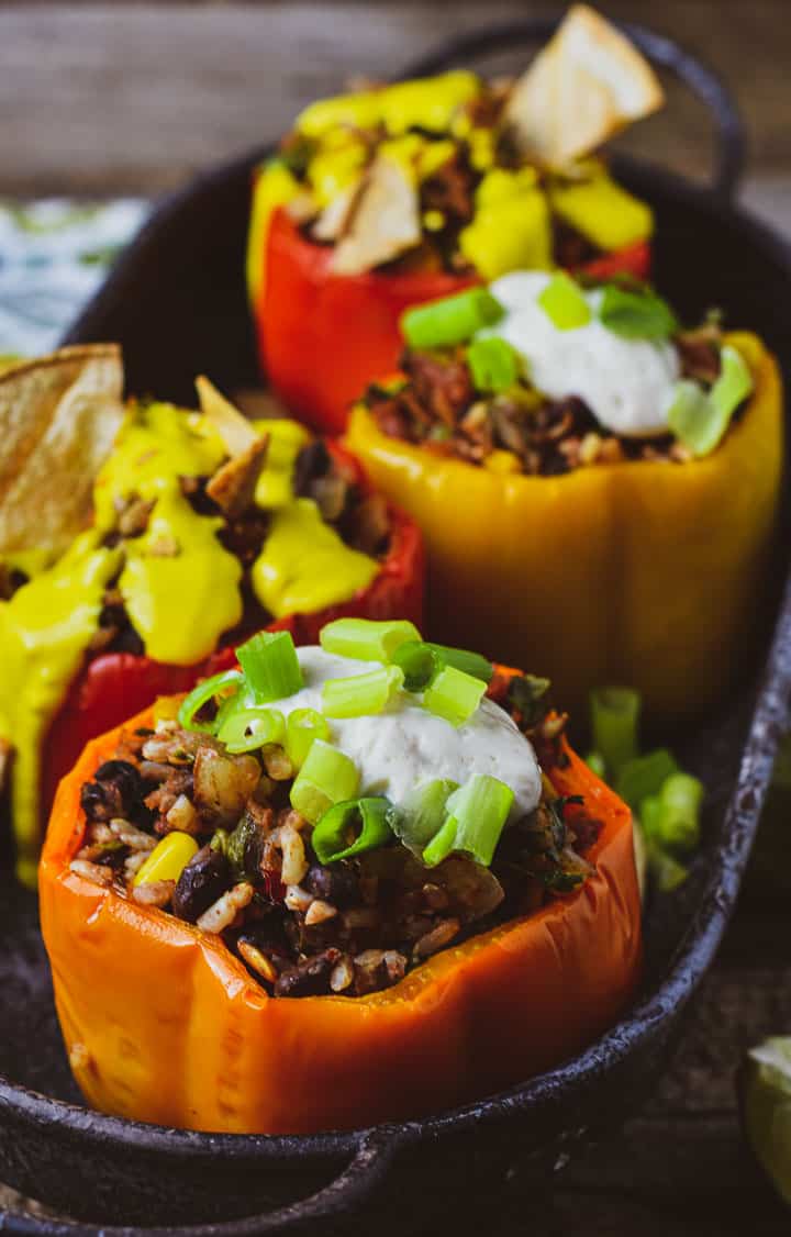 Vegan stuffed bell peppers in trays with onions and sour cream.