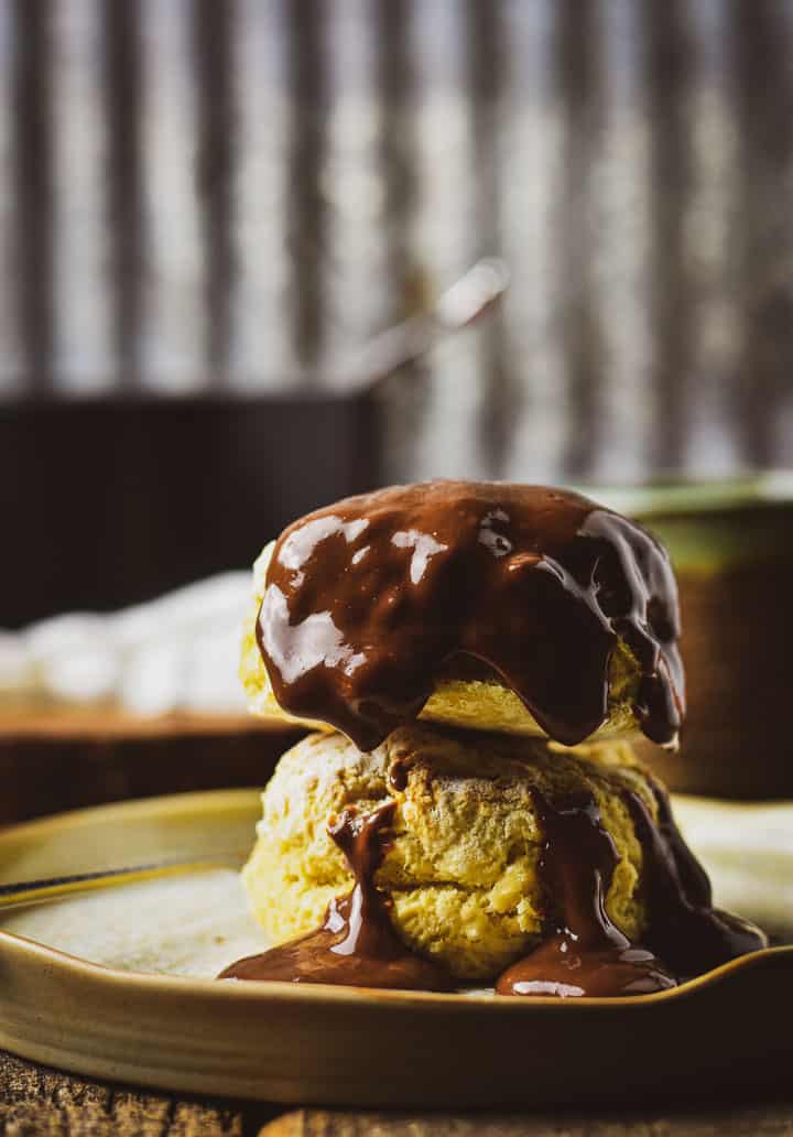 Vegan chocolate gravy drizzled over two biscuits.