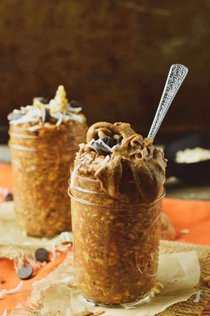 Vegan pumpkin pie overnight oats with a spoon and covered with almond butter.