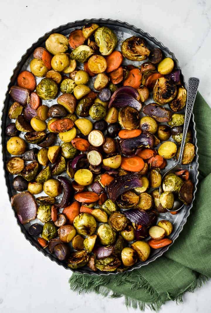 Holiday oven roasted vegetables on tray with spoon.