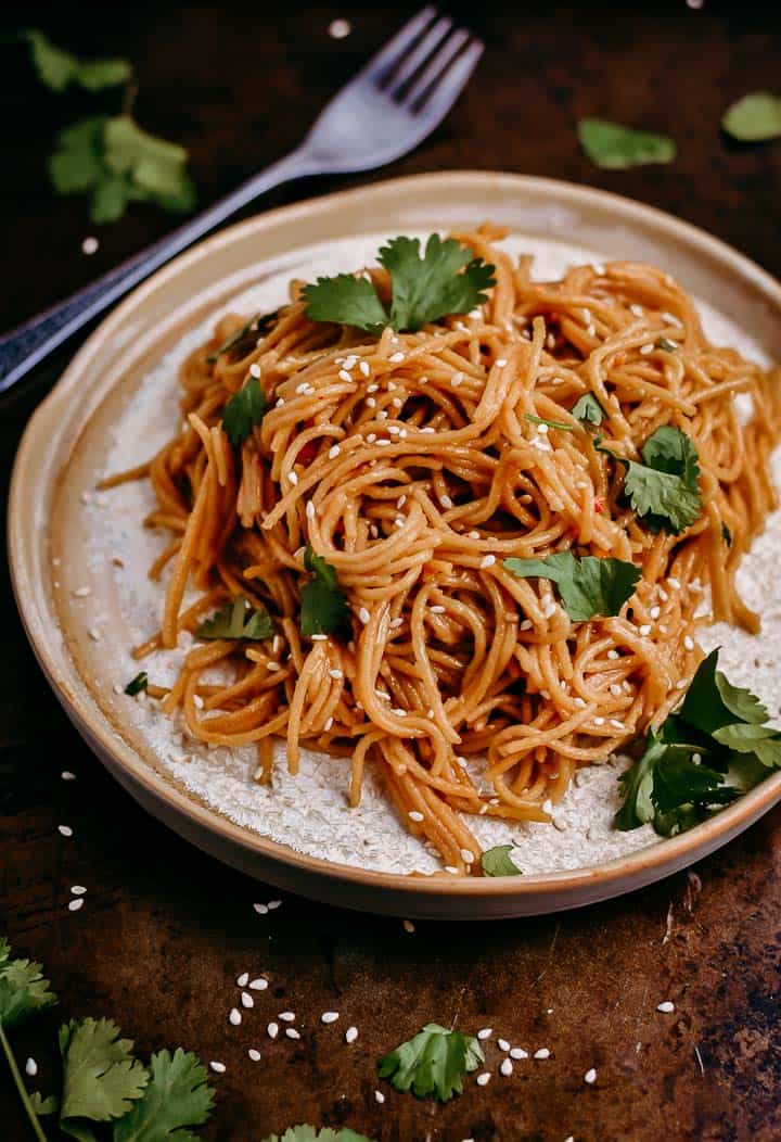 Sweet chili garlic instant pot noodles on plate with cilantro and sesame seeds.
