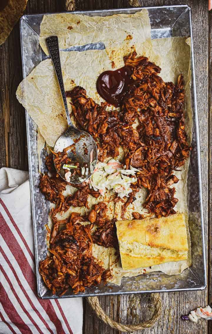 Vegan pulled pork on tray with spoon, slaw, and bread.