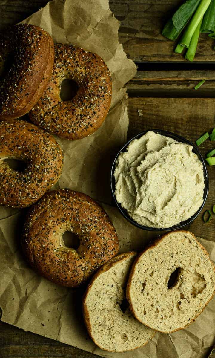 Bagels on paper sack with bowl of cream cheese.