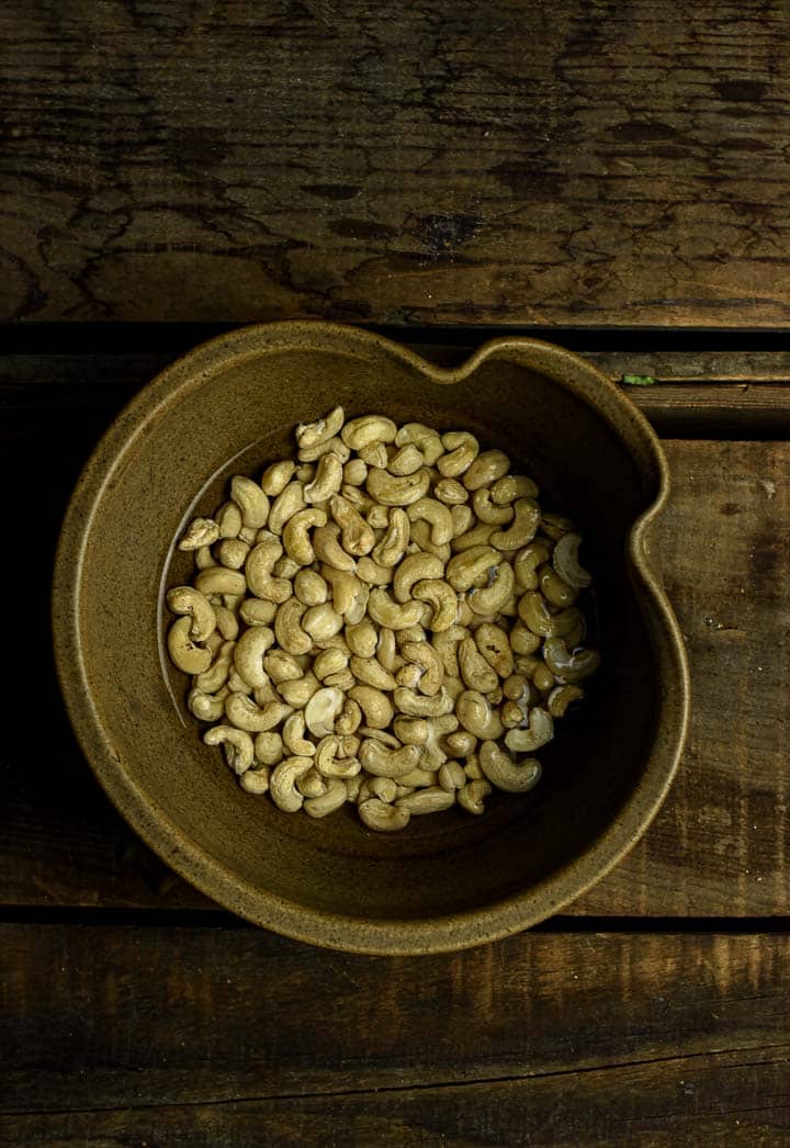 Raw cashews soaking in bowl of water.