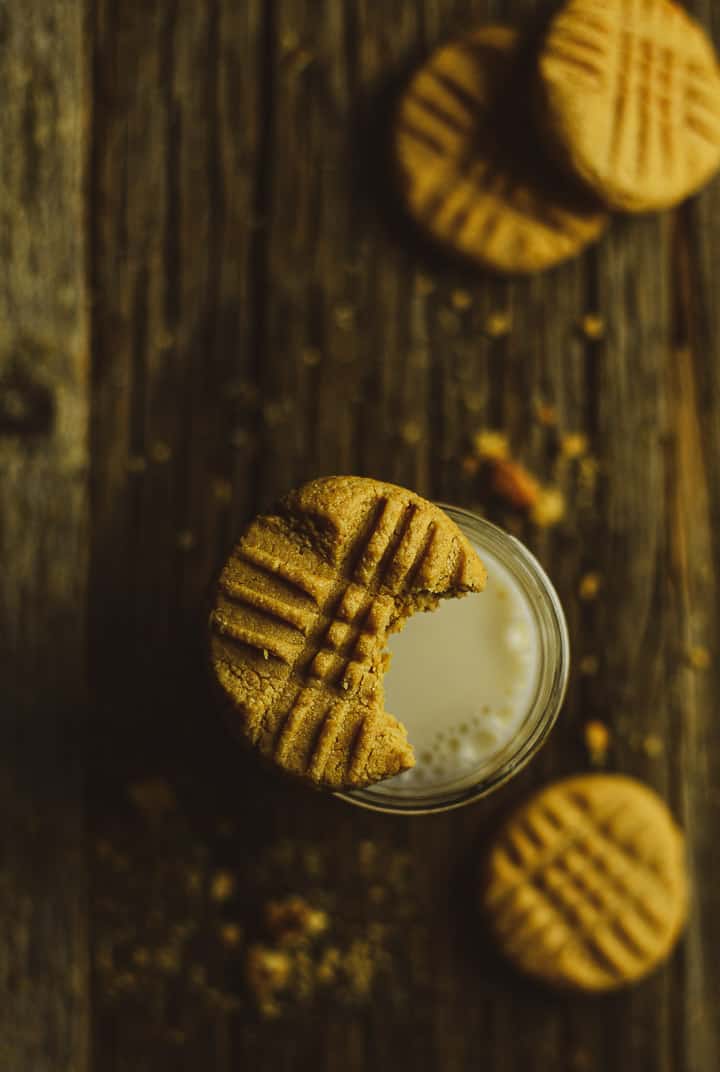 Peanut butter cookie with a bite on top of glass of milk.