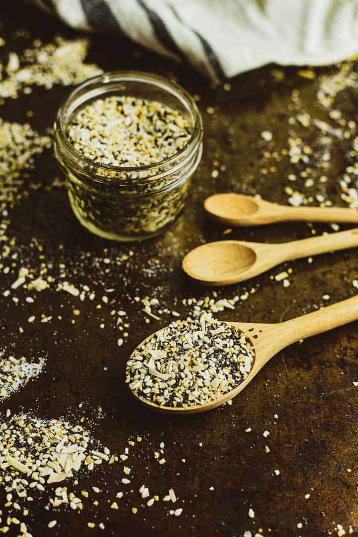 Everything bagel seasoning with wooden measuring spoon and glass jar.