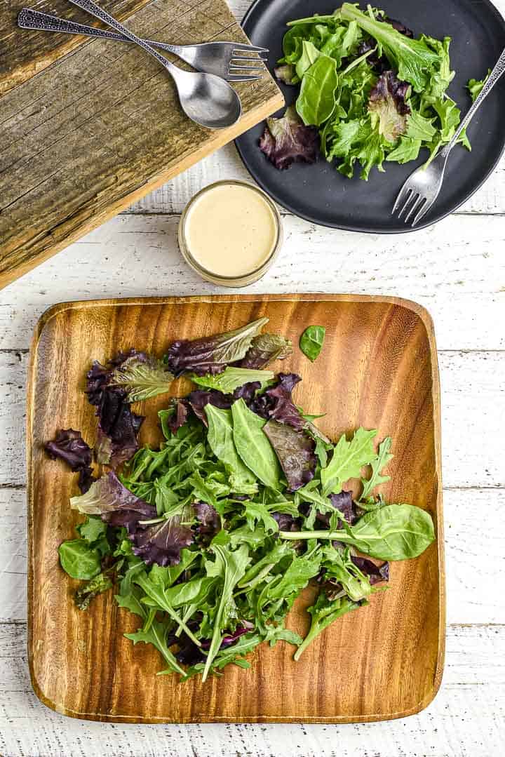 Salad on wooden plate with tahini dressing in bottle