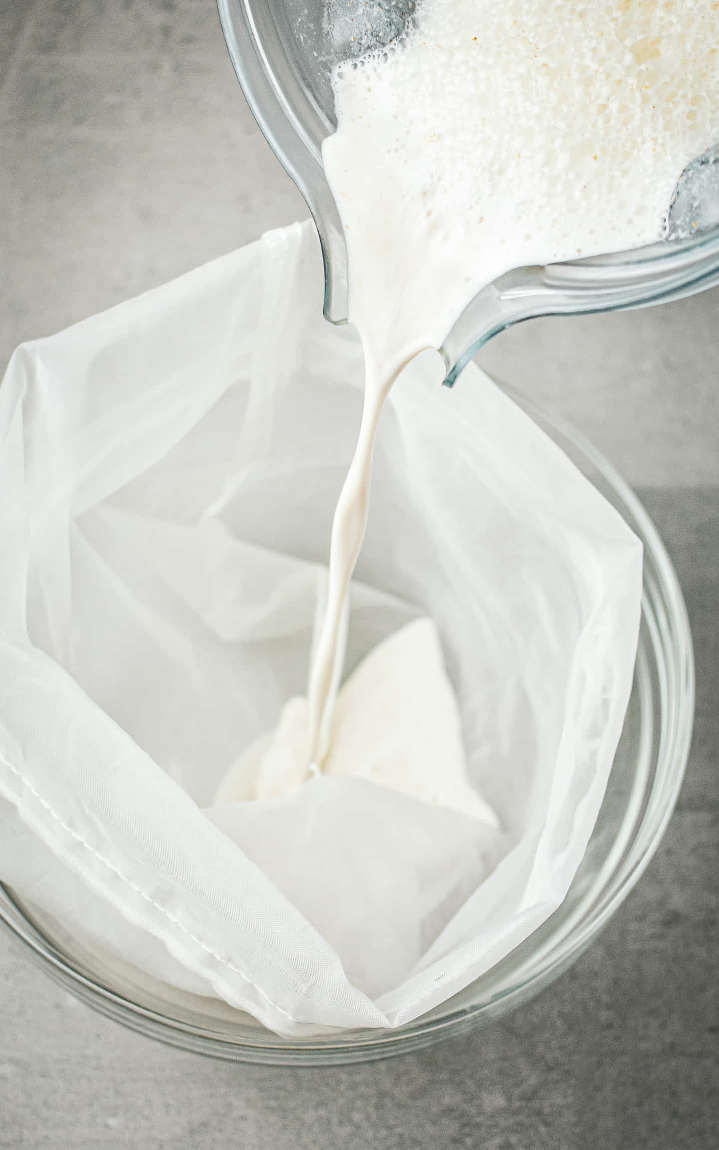 Almond milk being poured through a nut milk bag.