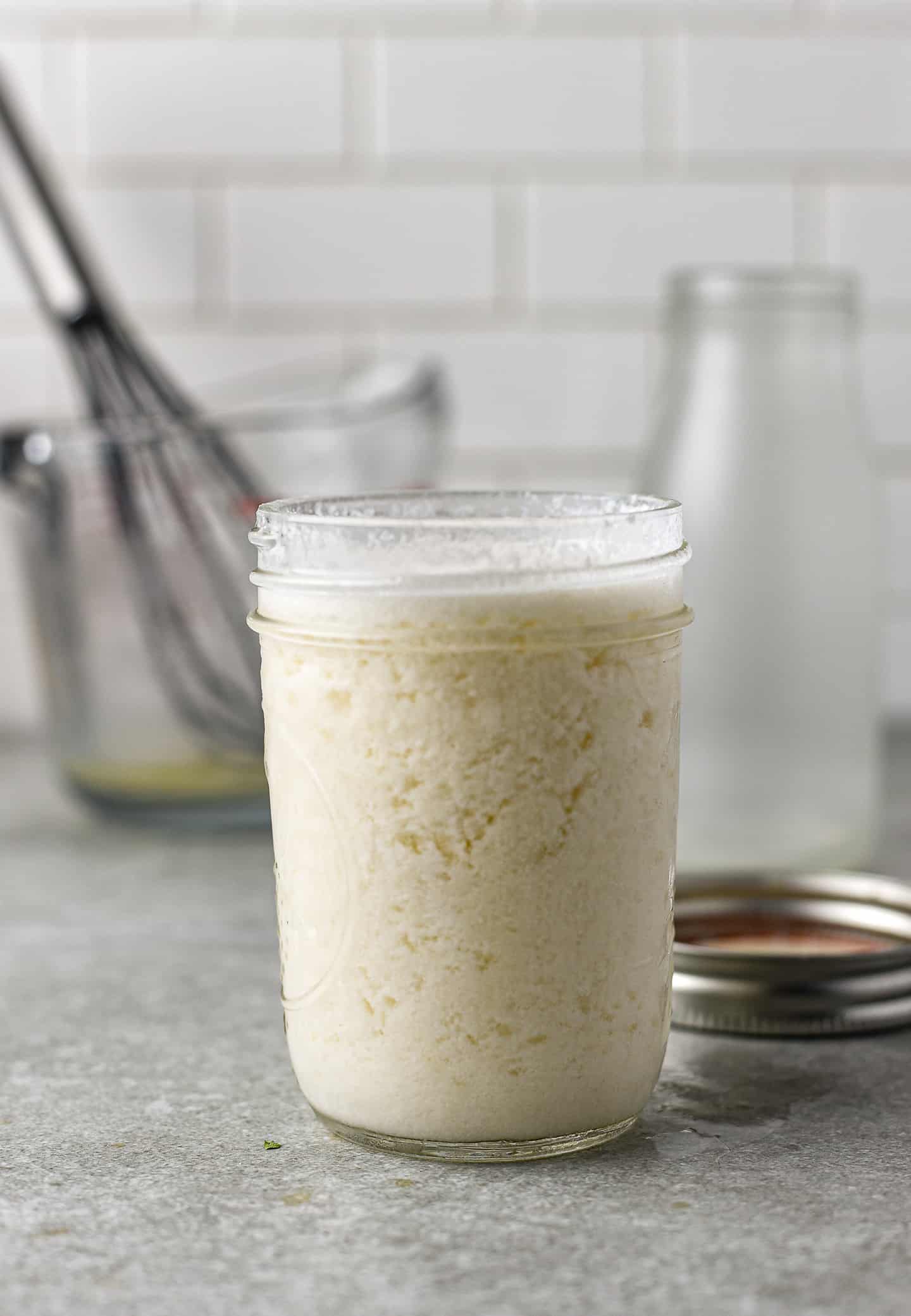 Curdled vegan buttermilk in glass jar.