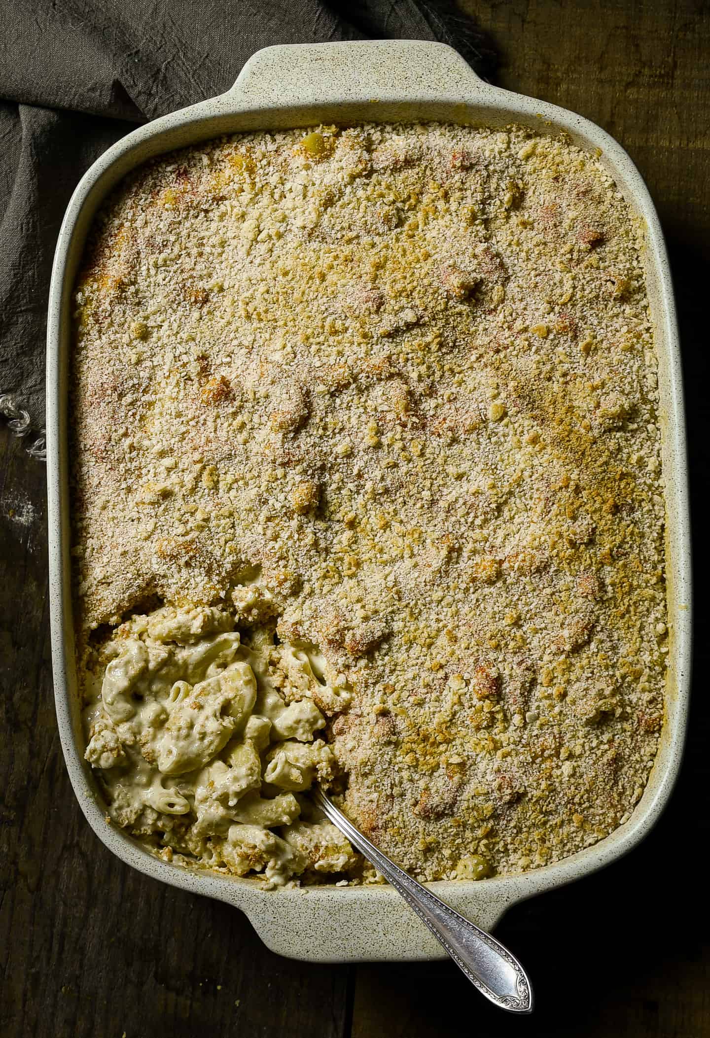Spoon in casserole dish with baked mac and cheese.