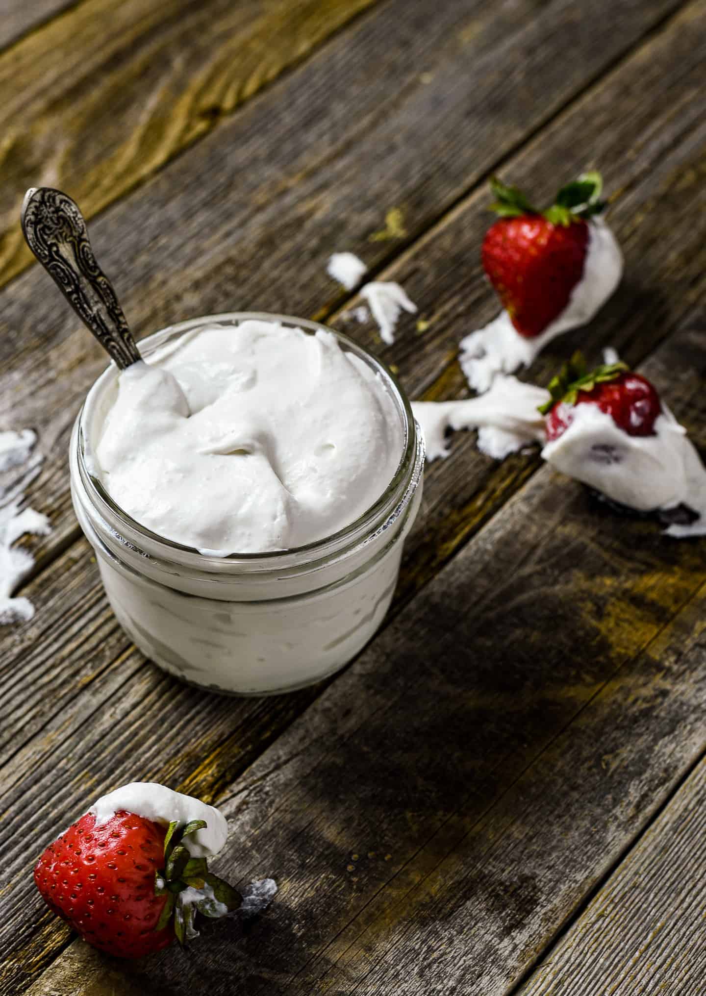 Jar of vegan whipped cream with starwberries.