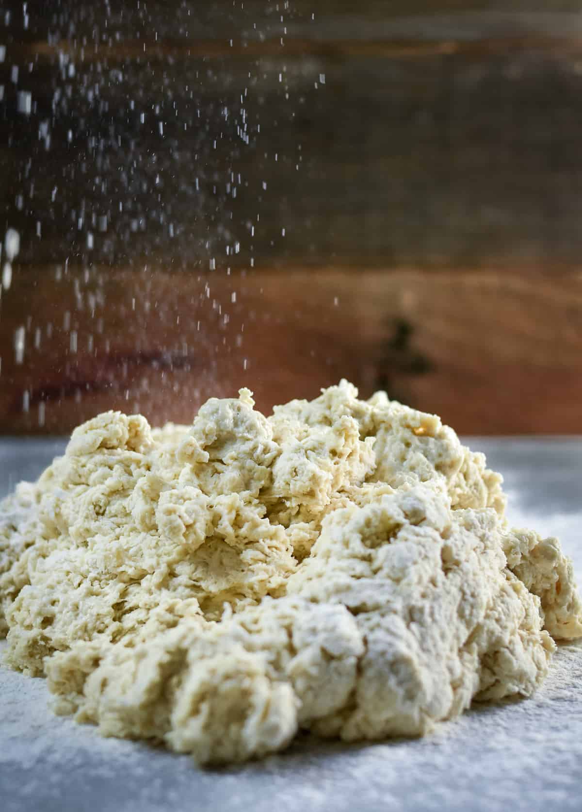 Flour being sprinkled on top of biscuit dough.