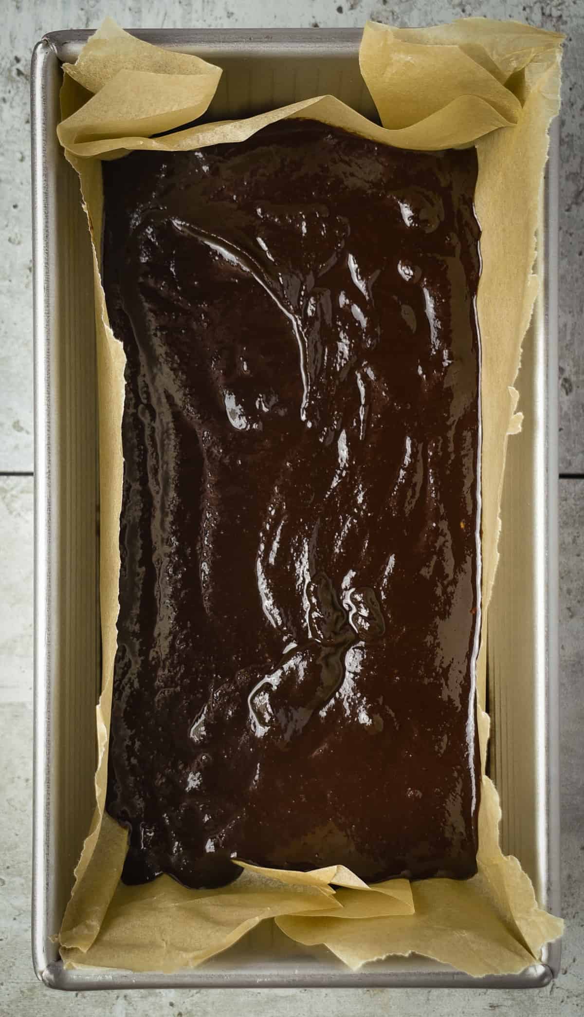 Melted fudge ingredients in loaf pan lined with parchment paper.