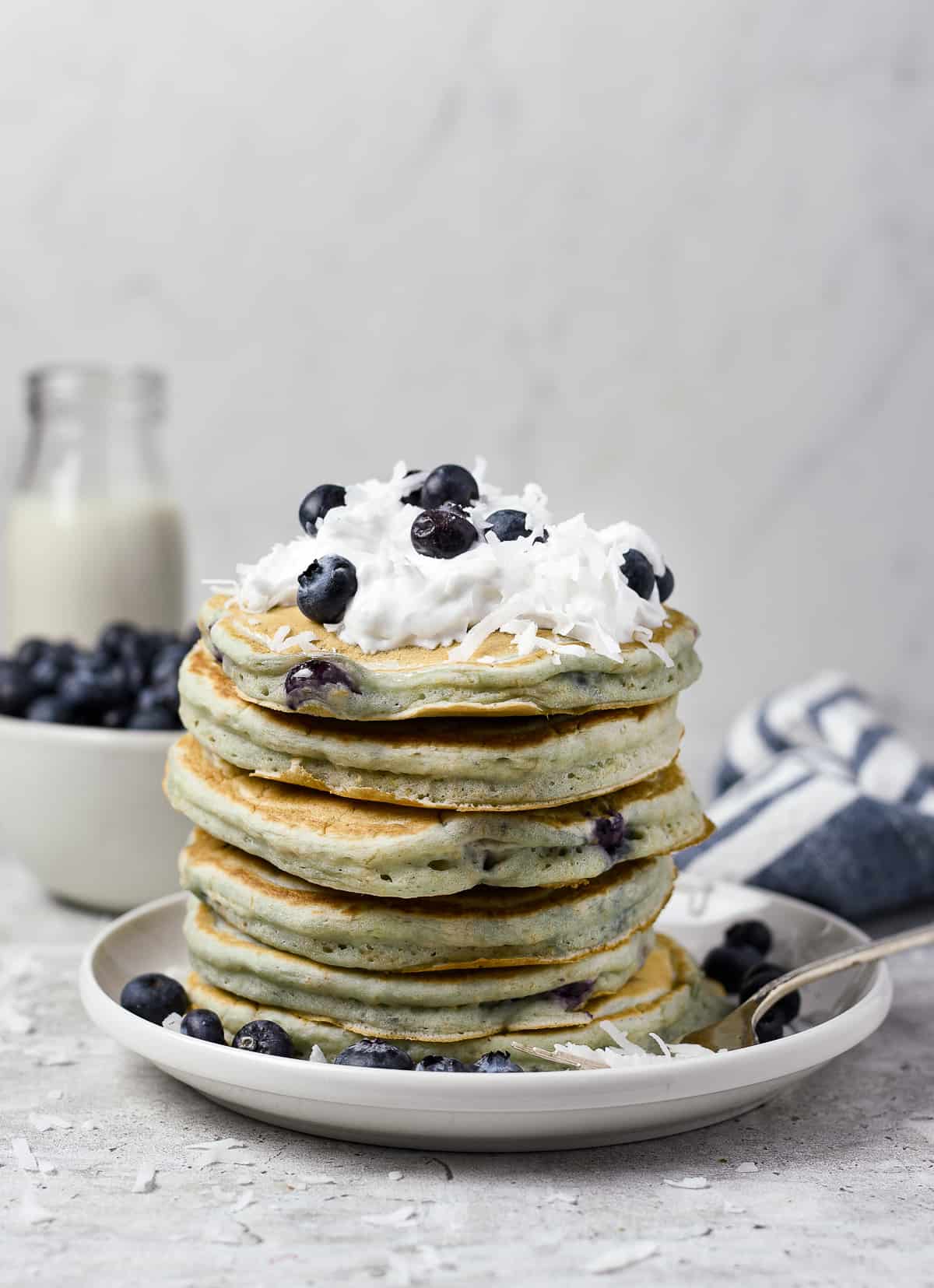 Stack of pancakes with whipped cream and blueberries.
