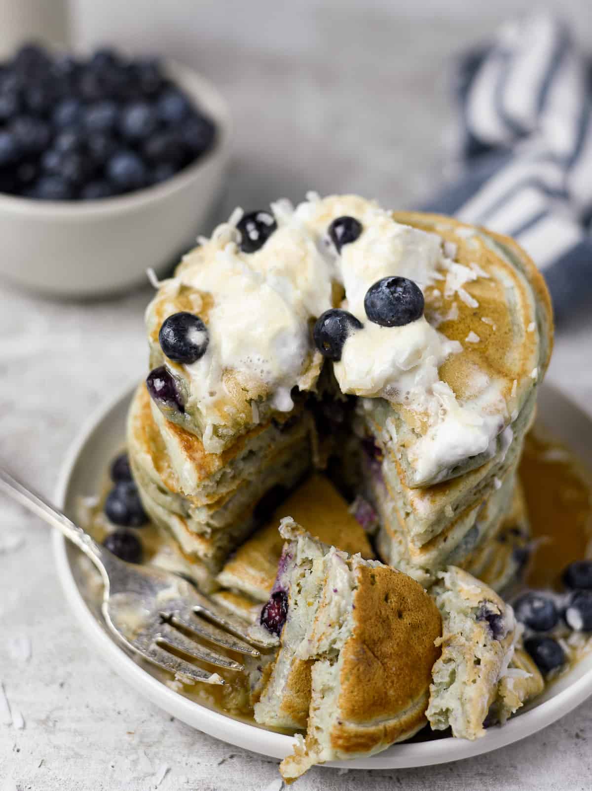 Blueberry pancakes on plate with fork and sliced.