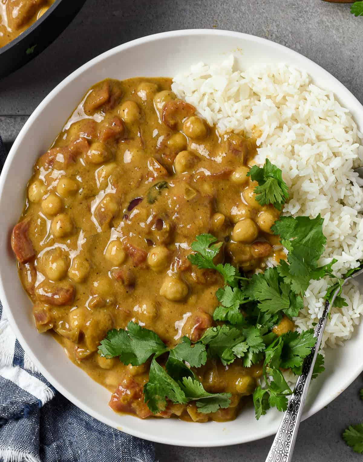 Chickpea curry in bowl with rice and cilantro.