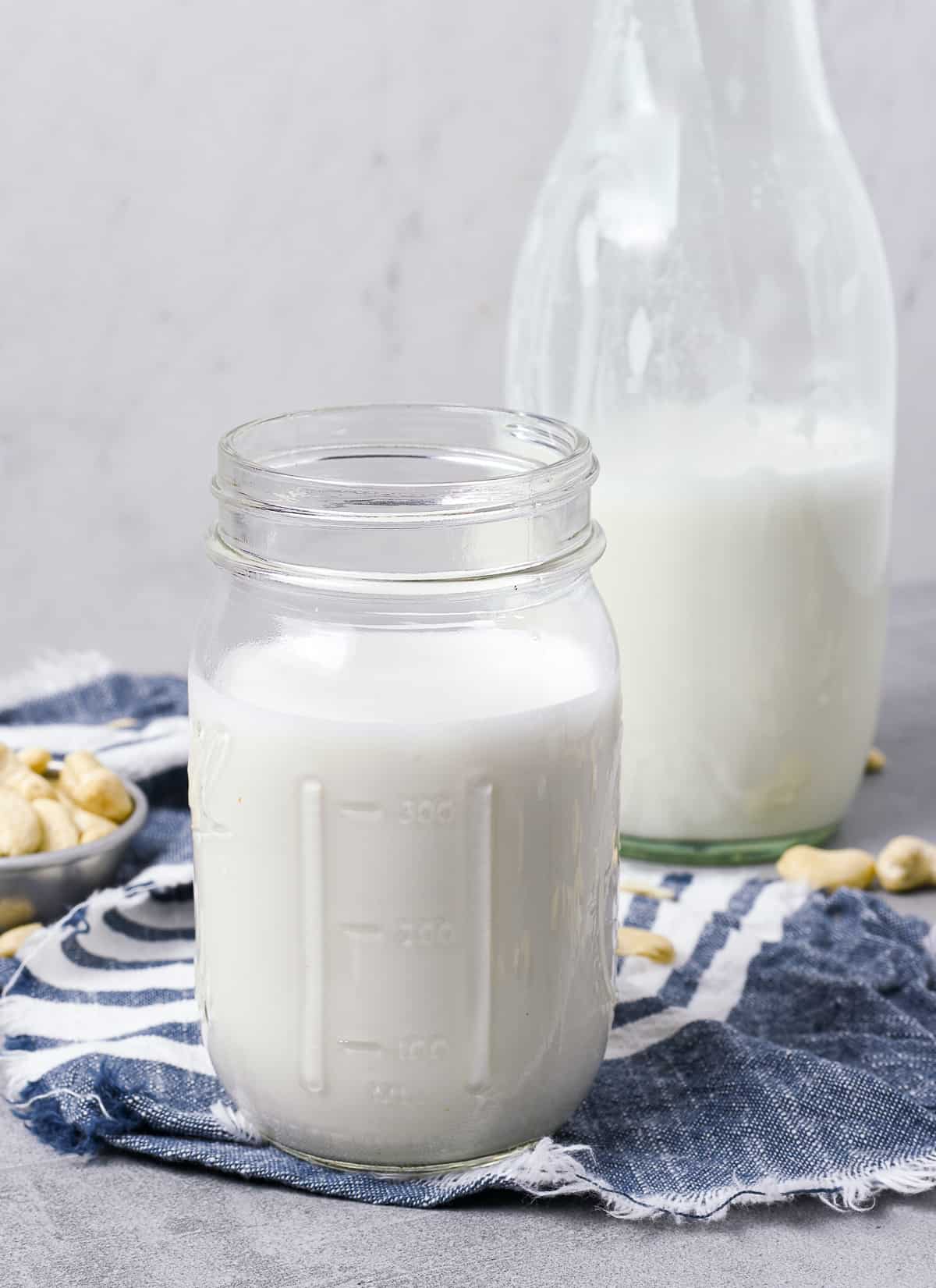 Cashew milk in glass jar and a milk bottle.