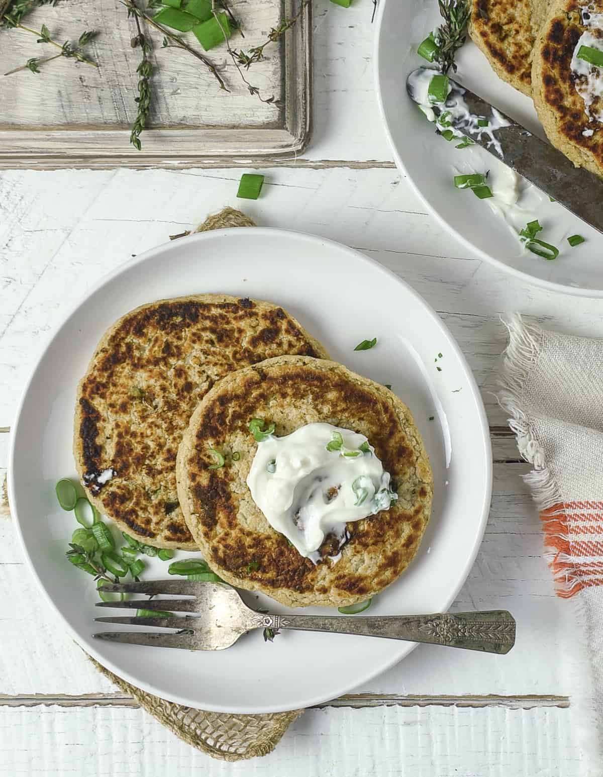 Potato pancakes on plate topped with sour cream.