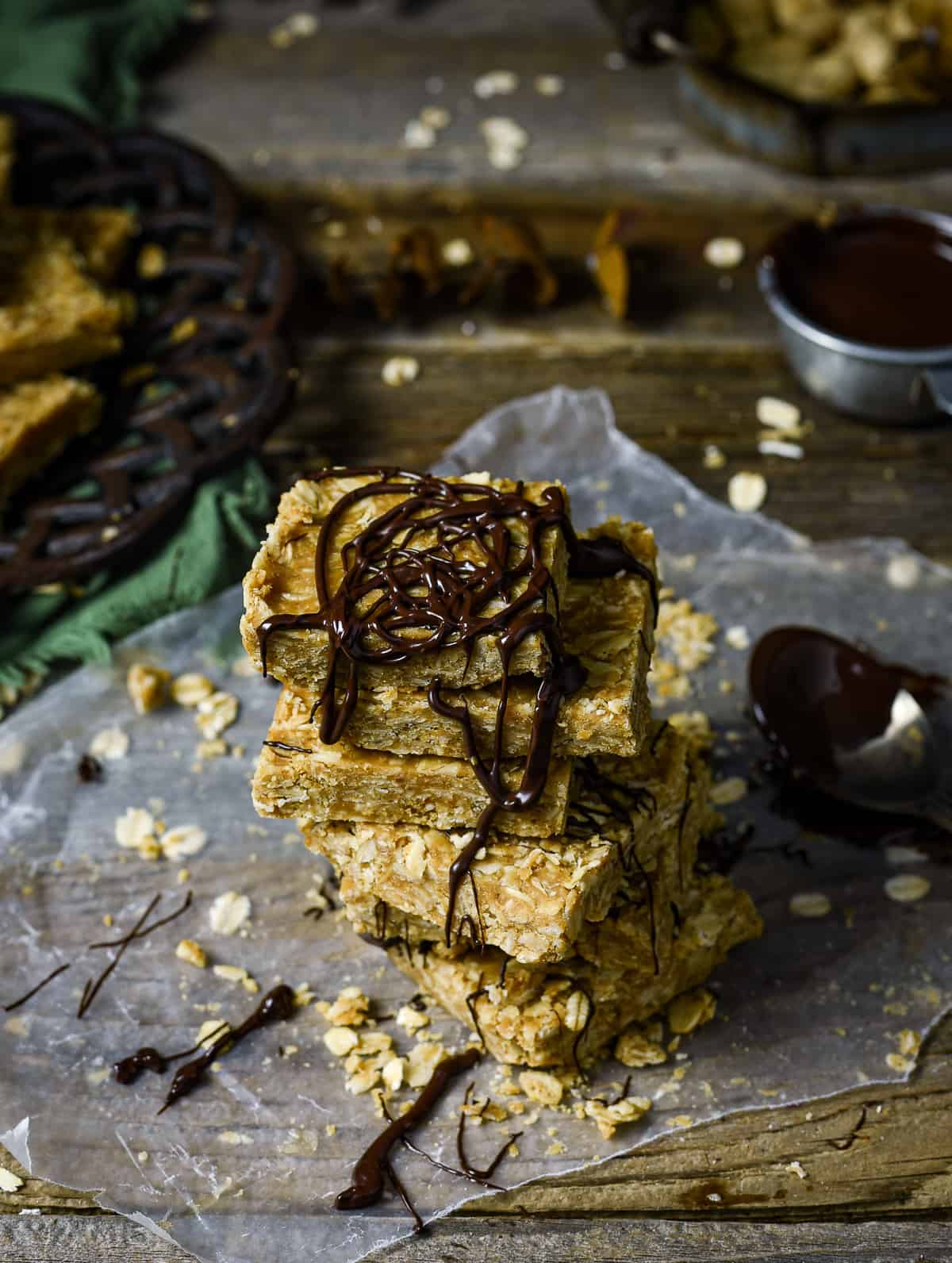 Peanut butter oatmeal bars stacked and drizzled with chocolate.