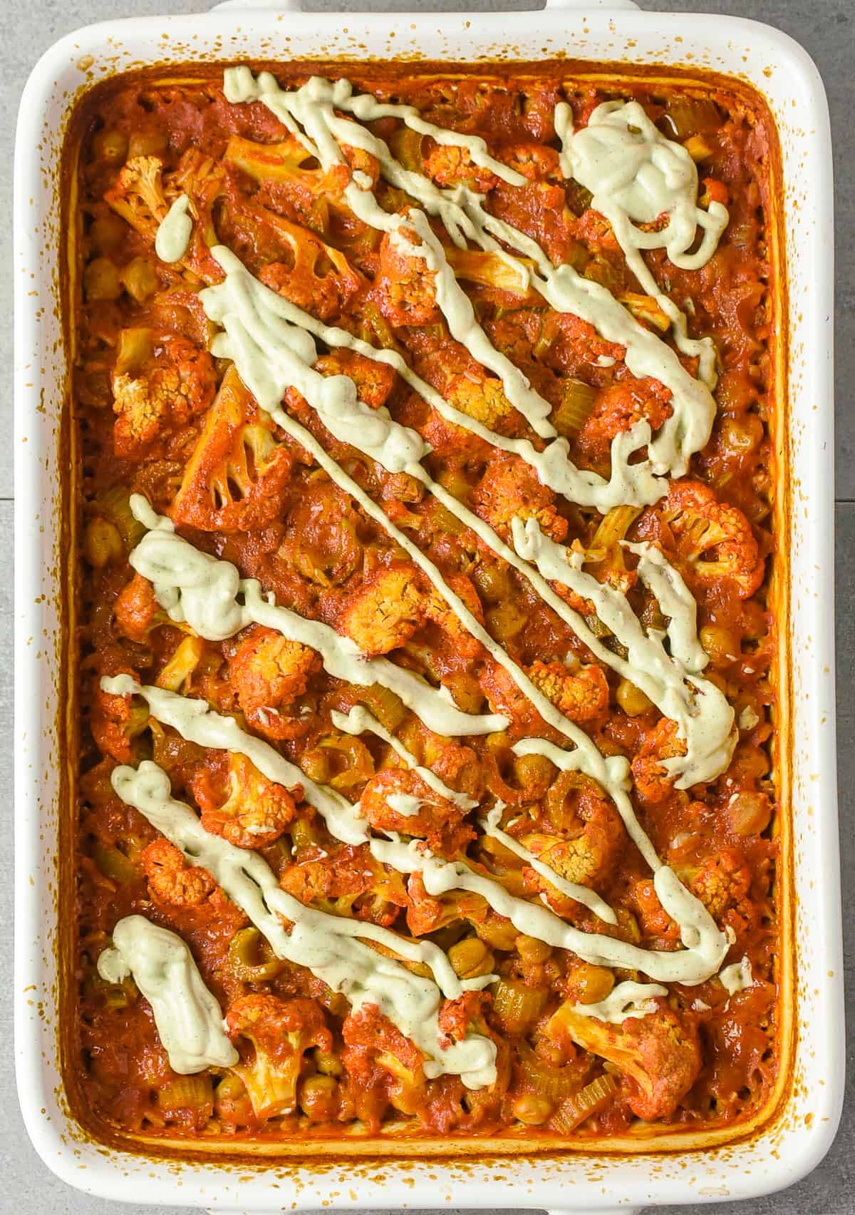 Buffalo chickpea cauliflower casserole topped with vegan ranch dressing.