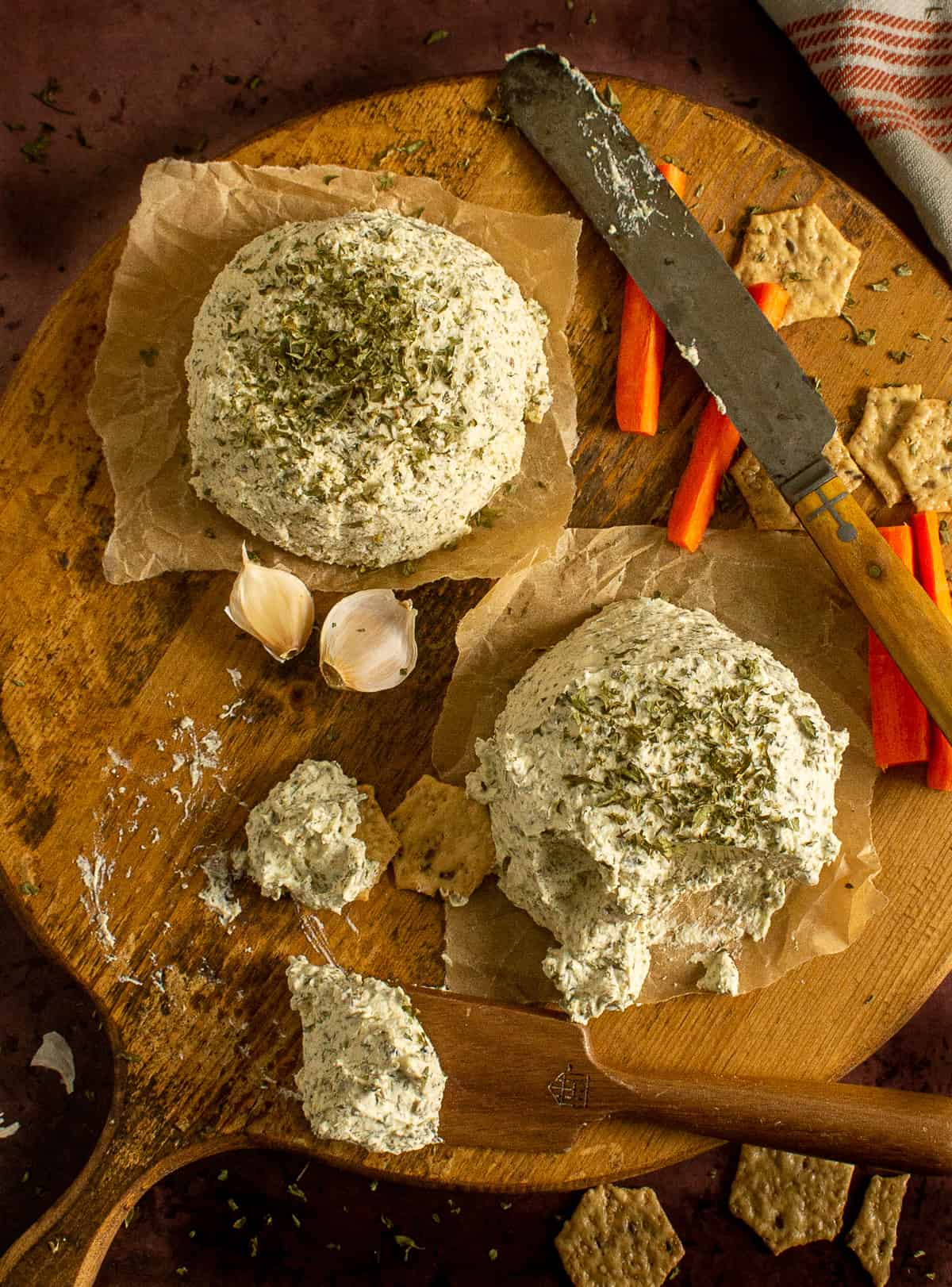 garlic herb vegan cheese spread on board with crackers and knives.