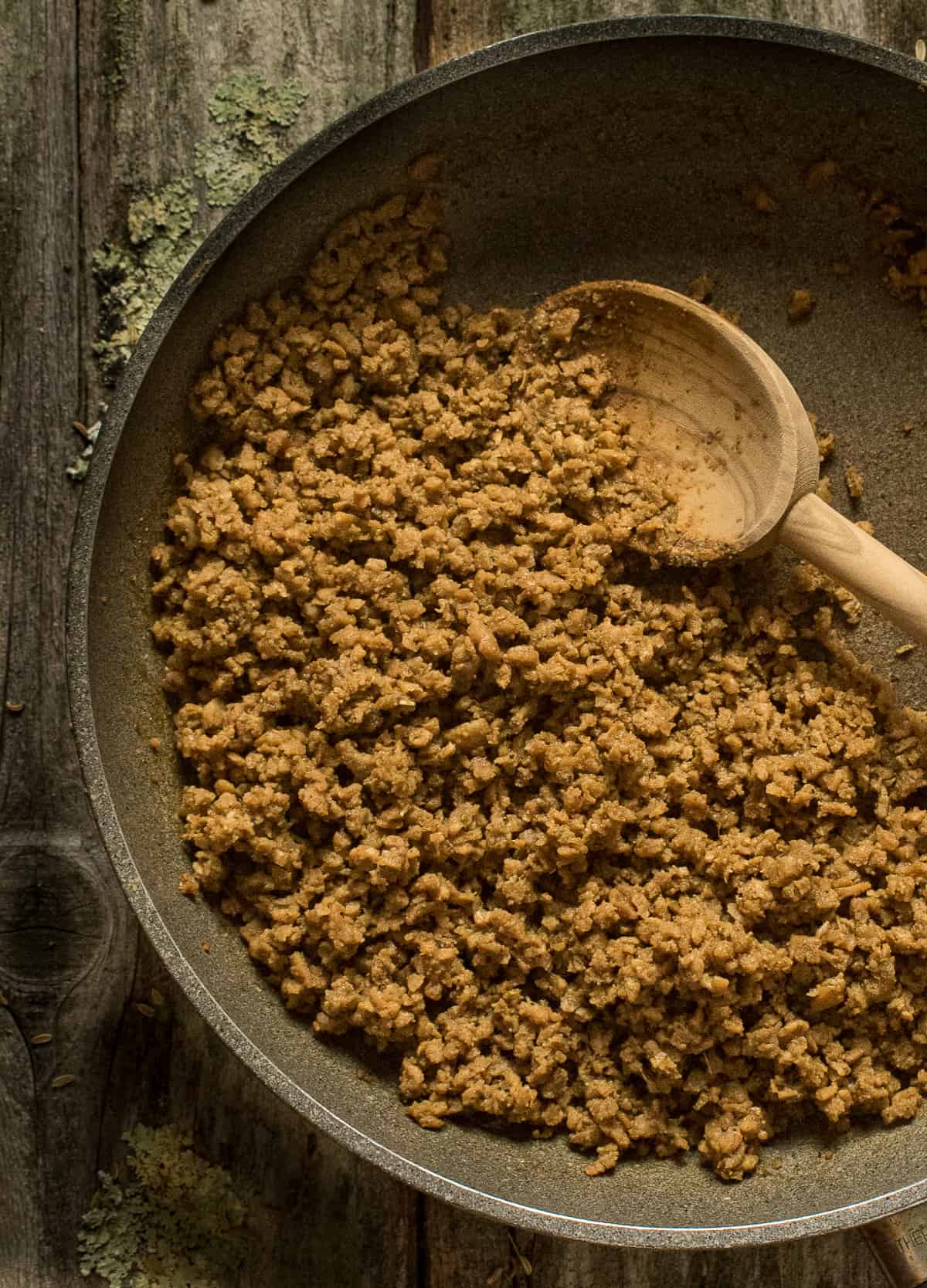 vegan sausage crumbles in nonstick skillet with spoon