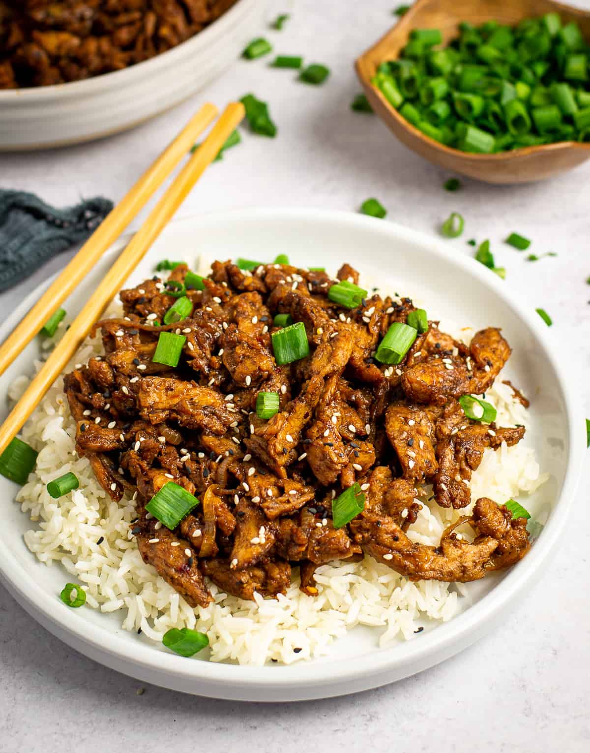 Vegan bulgogi on plate with rice and topped with green onions.