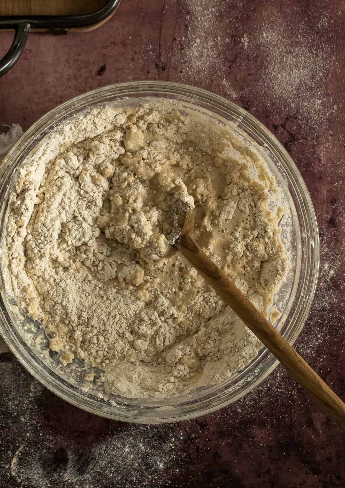 pizza dough in mixing bowl with wooden spoon