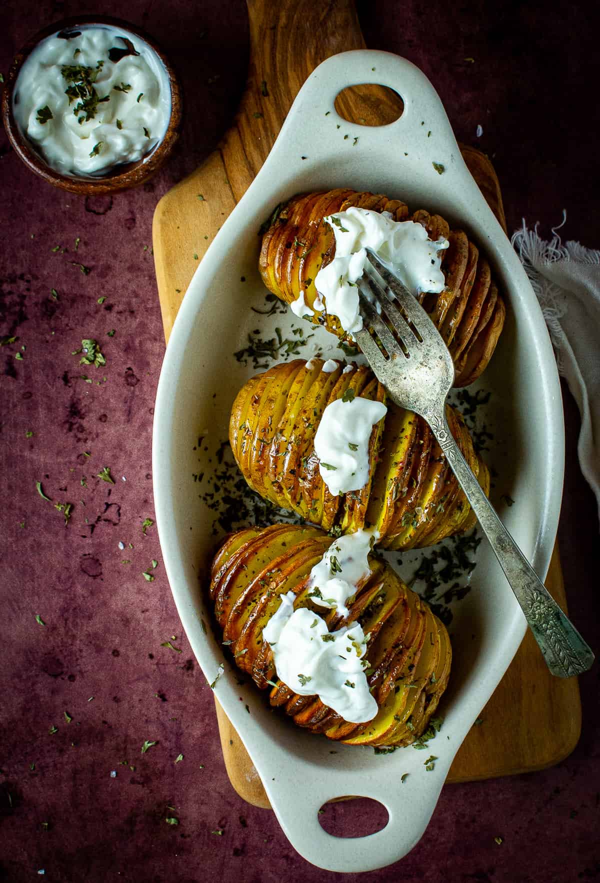 Hasselback potatoes in baking dish with sour cream.