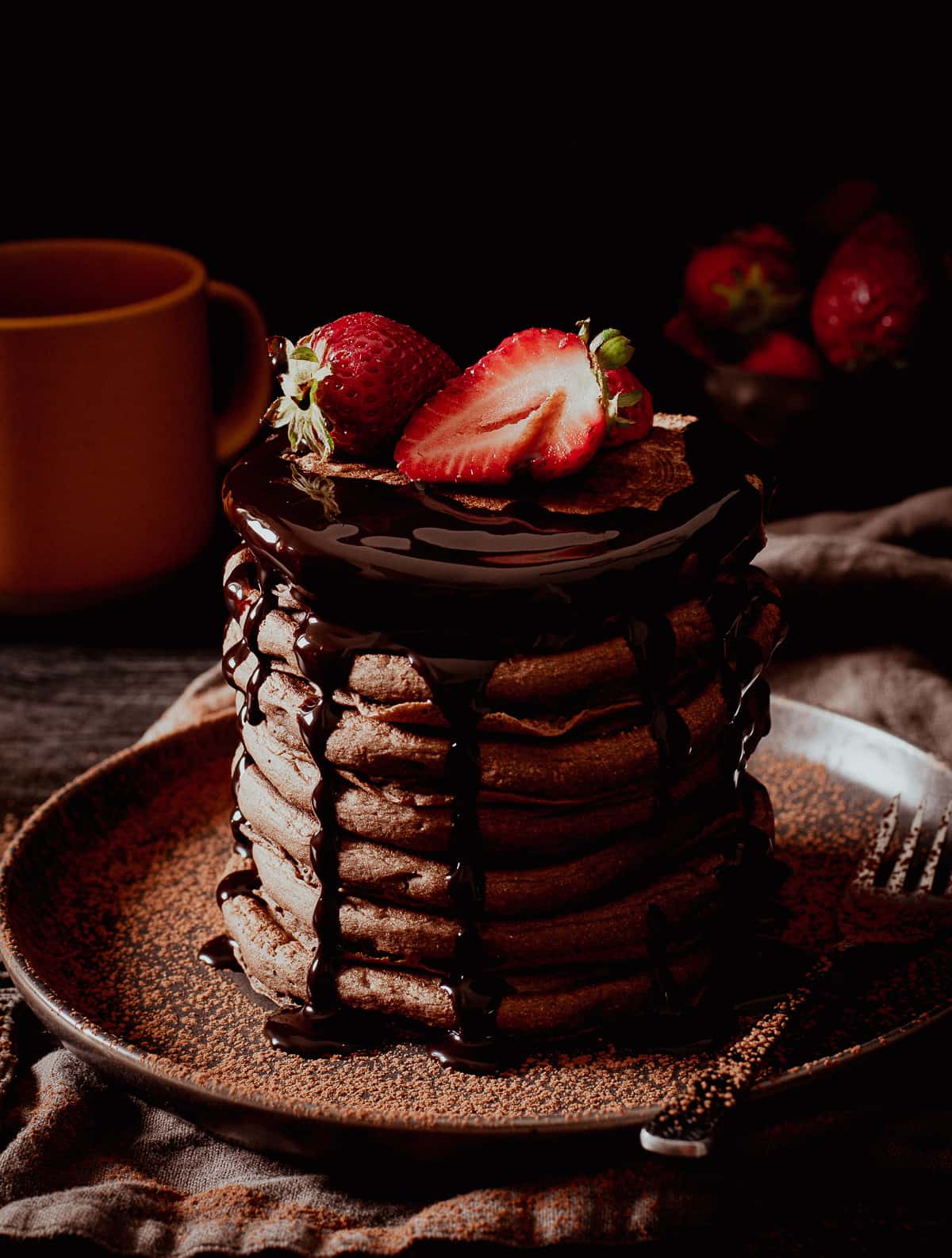 vegan chocolate pancakes with sauce and strawberries