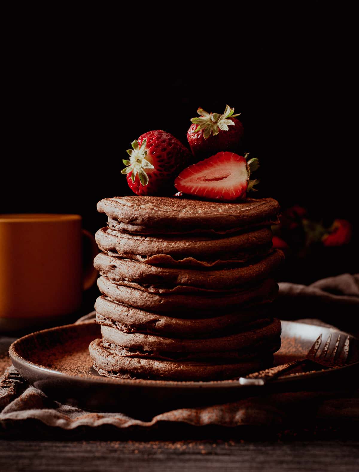 vegan chocolate pancakes stacked with strawberries