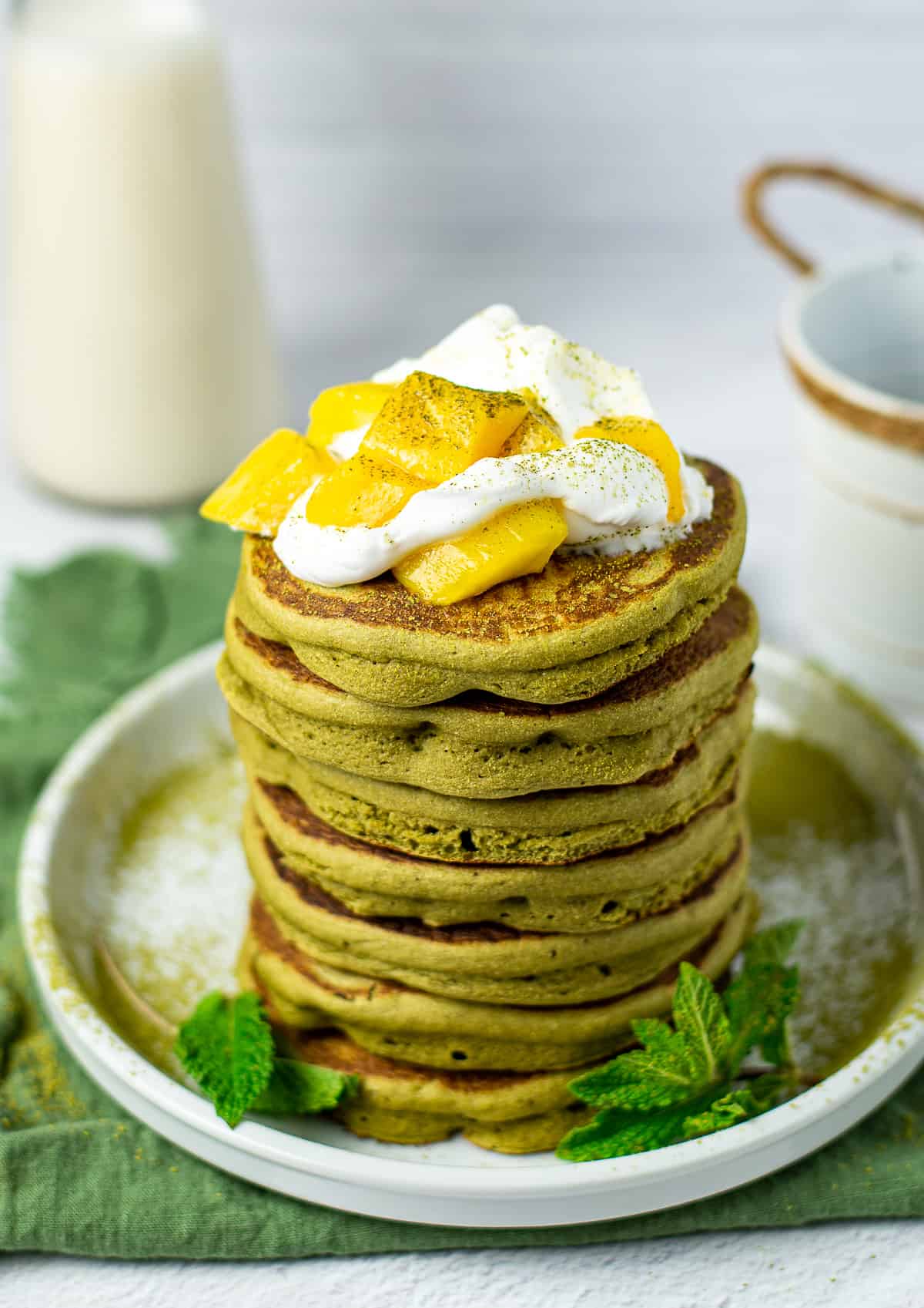 vegan matcha pancakes with whipped cream and mango.