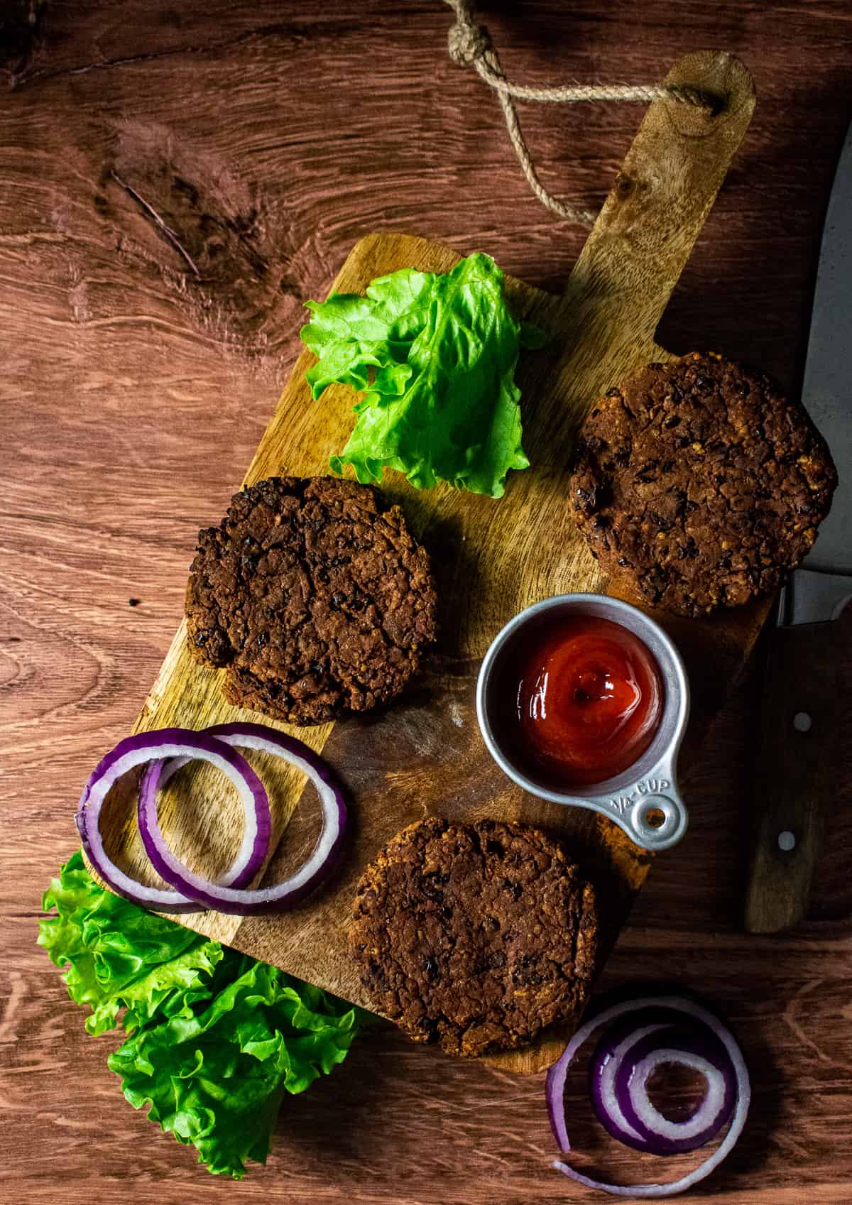 black bean burger patties on cutting board with lettuce and onion