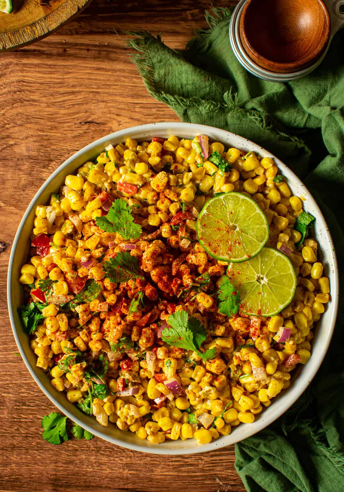 Mexican street corn salad in bowl with slices of lime.