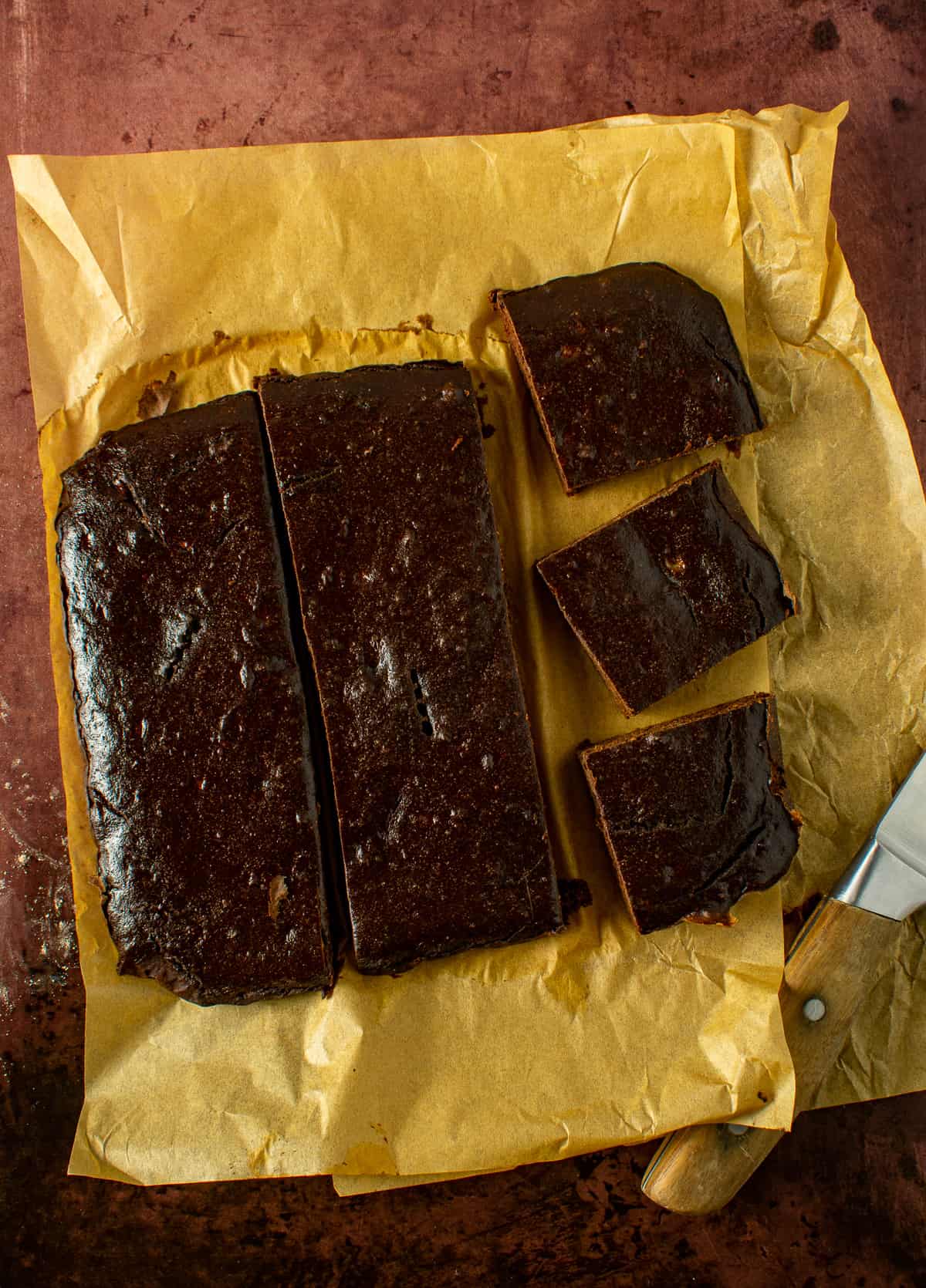 vegan brownies on parchment paper with knife.