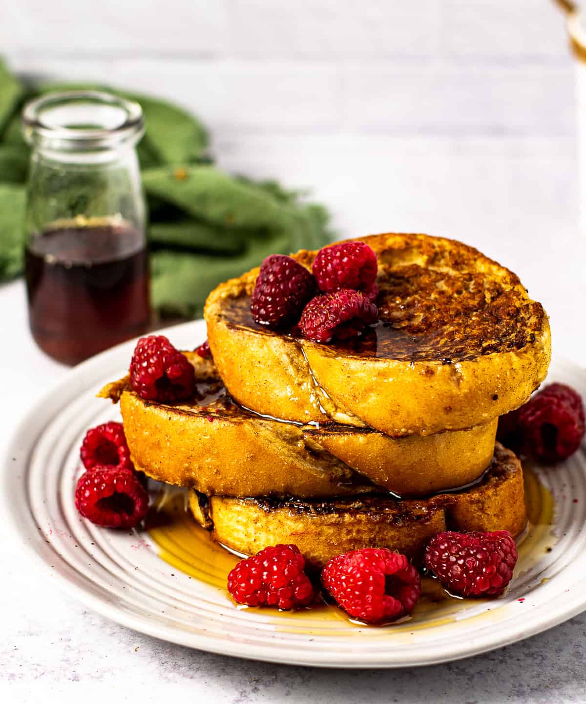vegan french toast on plate with syrup and raspberries