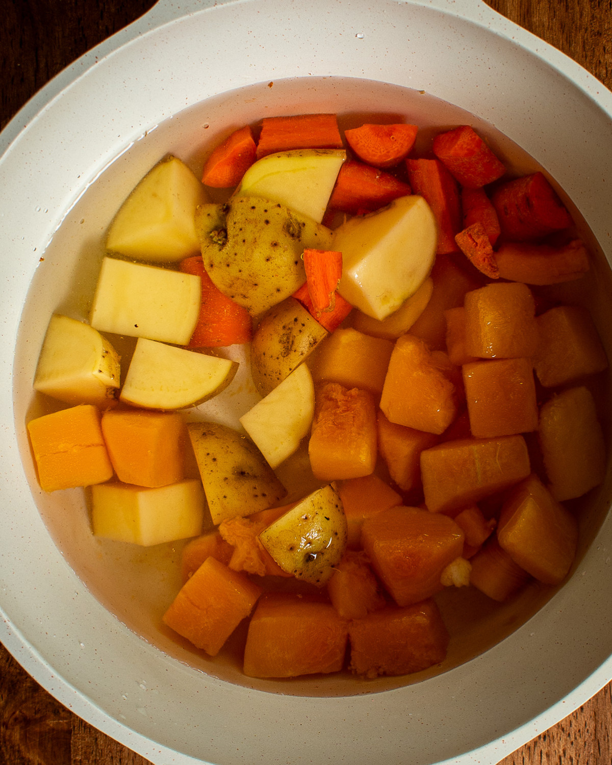 Boiled butternut squash, carrot, and potato in a pot for vegan cheese sauce