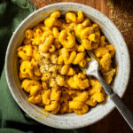 Bowl of creamy vegan butternut squash mac and cheese with black pepper and vegan parmesan.